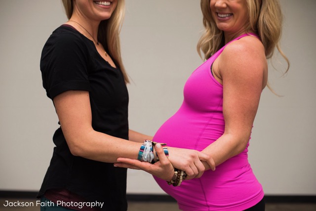 two women holding hands, one in third trimester and the other her doula