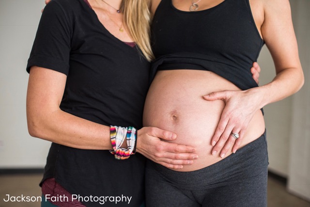 doula holding hand against a pregnant mom's belly