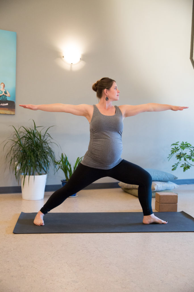 pregnant woman doing prenatal yoga pose warrior two