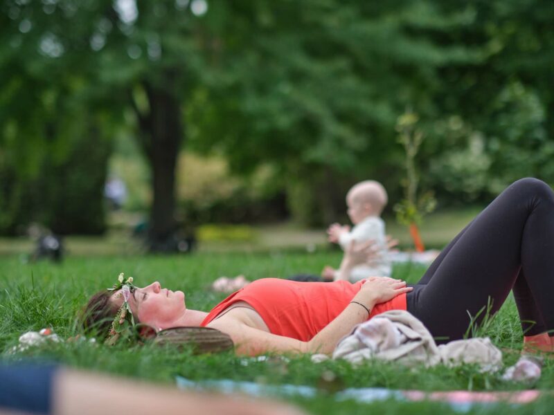 pregnant woman doing yoga outside with baby