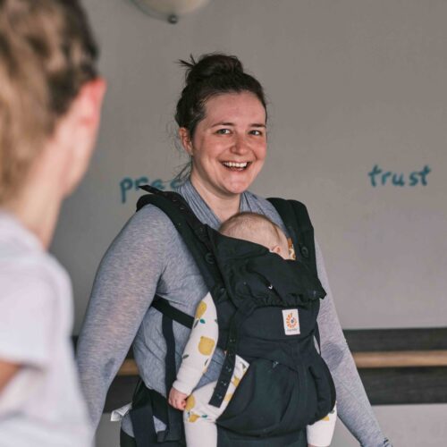 mother wearing her baby in a carrier in a workout class