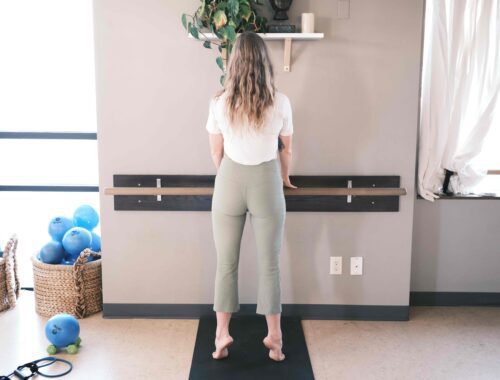 woman doing barre pose against the wall