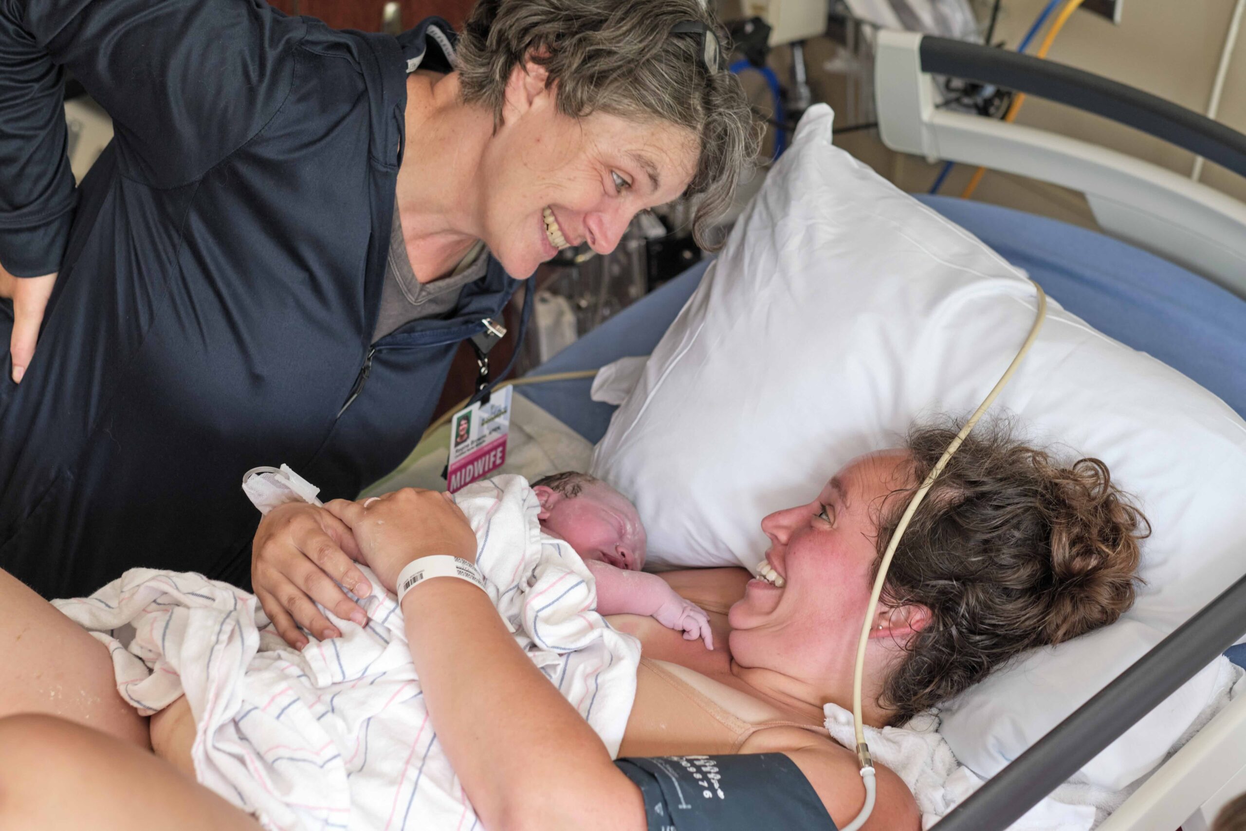 midwife and new mom smiling at each other after birth